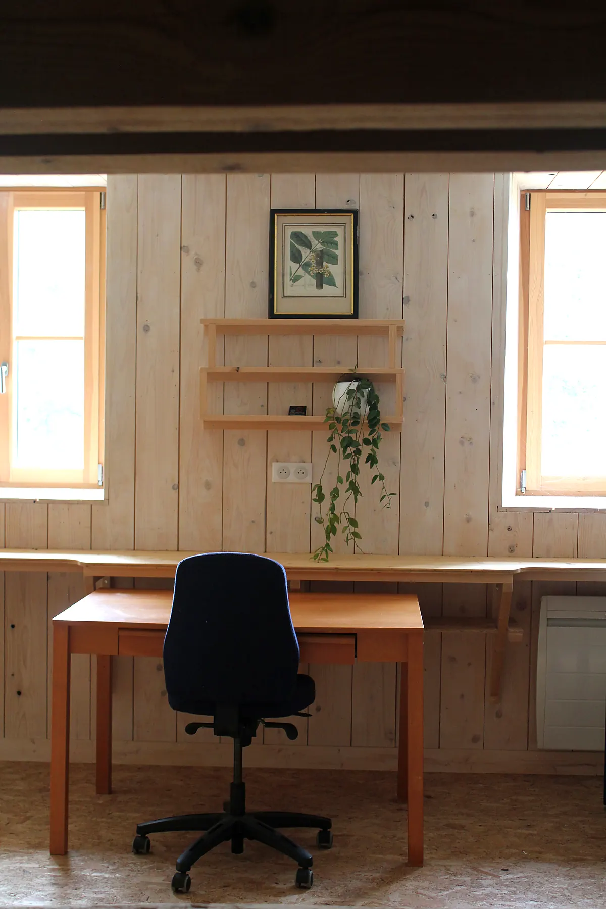 Un poste de travail individuel près d’une fenêtre et de plantes.